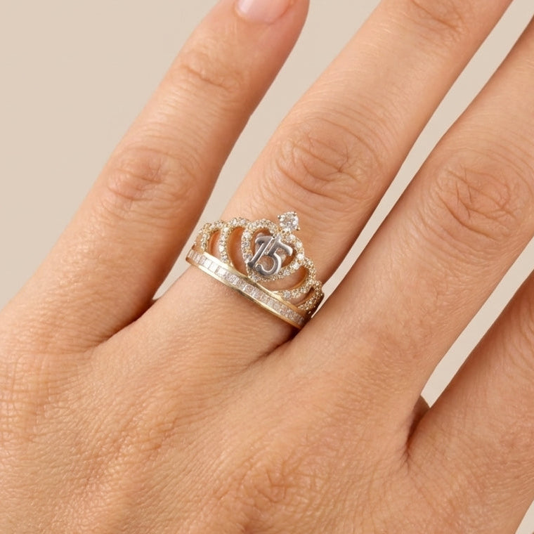 Hand wearing a ring with a crown design on a neutral background