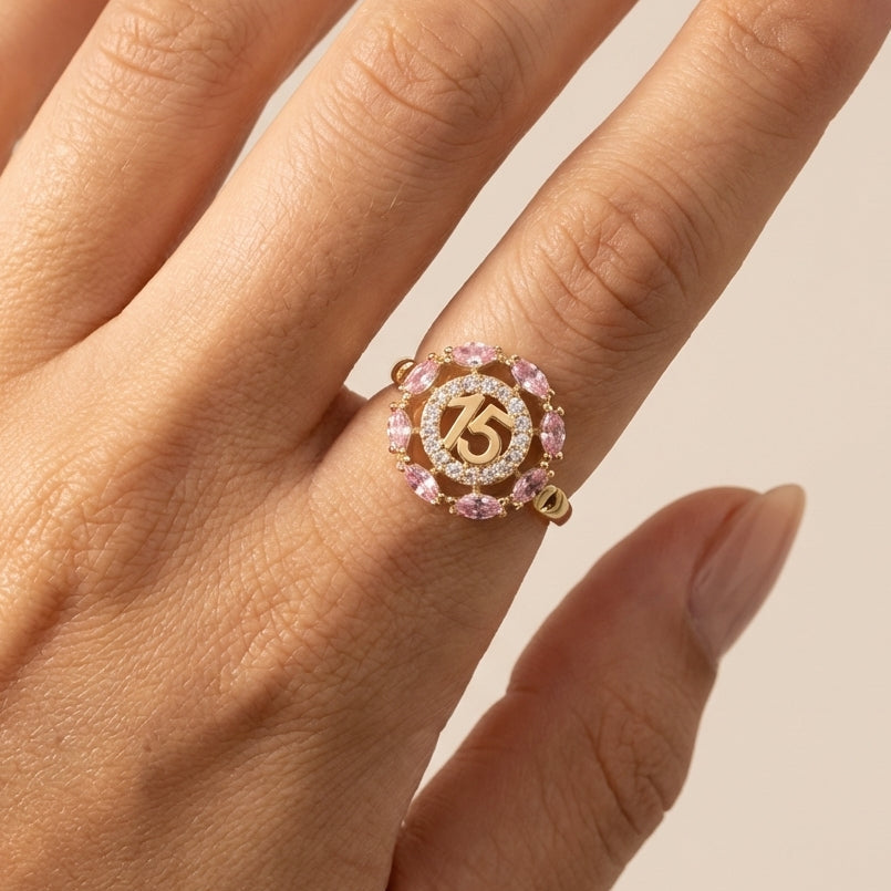 Gold ring with pink gemstones on a hand against a beige background