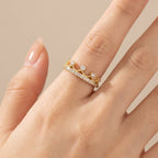 Gold ring with small diamonds on a hand against a beige background