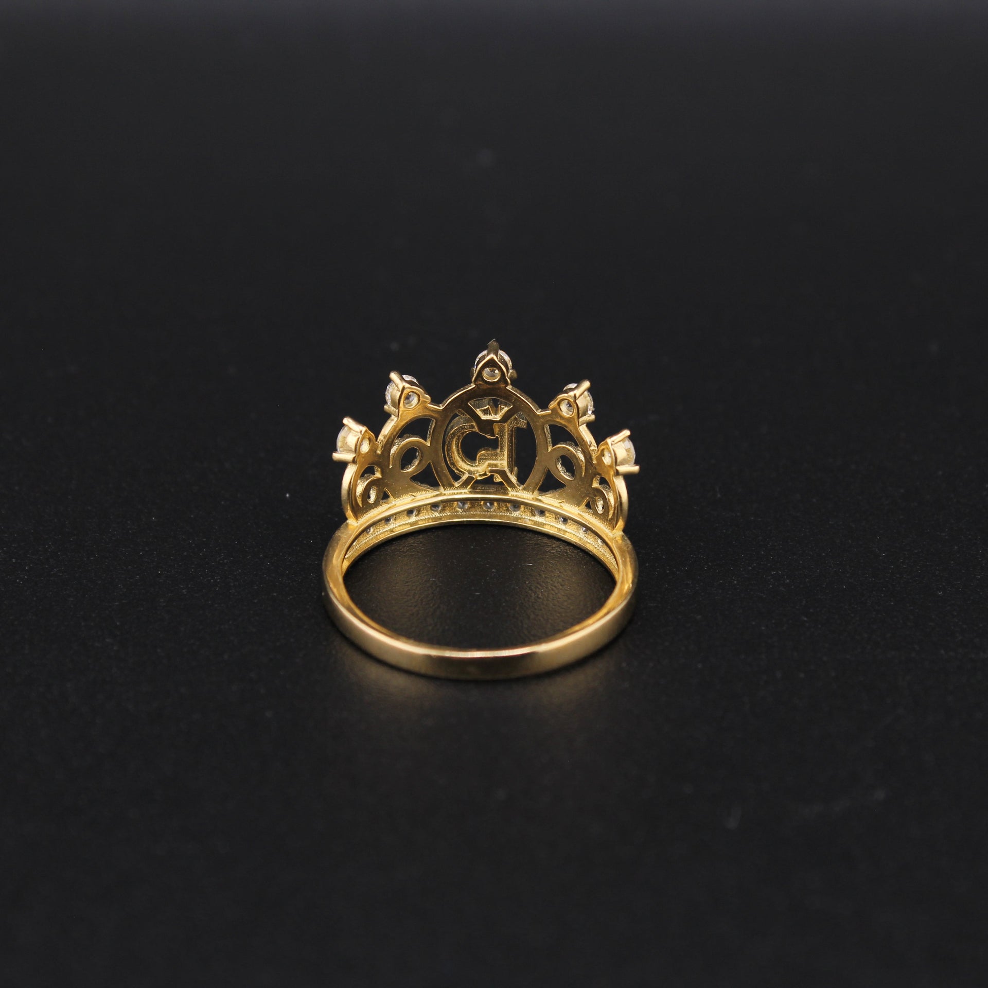 Gold crown-shaped ring on a black background